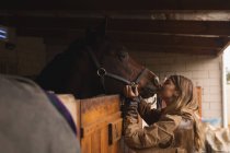 Adolescente caressant un cheval dans le ranch — Photo de stock