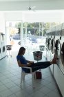 Concentrated woman reading a book at laundromat — Stock Photo