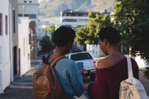 Visão traseira de irmãos gêmeos usando telefone celular na rua da cidade — Fotografia de Stock