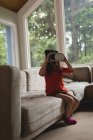 Chica usando auriculares de realidad virtual en la sala de estar en casa - foto de stock