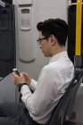 Young man using mobile phone while travelling in train — Stock Photo