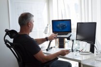 Hombre preparando el diseño arquitectónico en el ordenador portátil y el ordenador en casa - foto de stock
