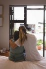 Visão traseira do fisioterapeuta abraçando a mulher idosa em casa — Fotografia de Stock