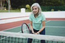 Концентрат старшої жінки, яка грає в теніс в тенісному корті — стокове фото