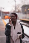 Giovane donna che parla al cellulare alla stazione ferroviaria — Foto stock