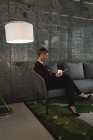 Бізнес-леді сидить на дивані і використовує мобільний телефон в офісі — стокове фото