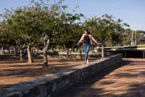 Женщина балансирует на стене в парке в солнечный день — стоковое фото