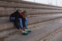 Athlète féminine attachant des lacets sur le site de sport — Photo de stock