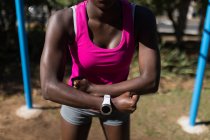Partie médiane de l'athlète féminine avec smartwatch sur l'exercice du poignet — Photo de stock