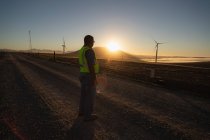 Задний вид инженера, стоящего на ветряной электростанции — стоковое фото