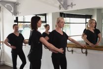 Trainer unterstützt junge Frau beim Stretching auf der Barre — Stockfoto