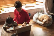 Madre e figlio utilizzando laptop e tablet digitale a casa — Foto stock