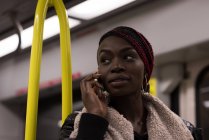 Молода жінка розмовляє по мобільному телефону під час подорожі в поїзді — стокове фото