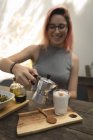 Молода жінка виливає каву з кавового чайника — стокове фото