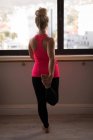Вид ззаду жінки, що виконує вправи в фітнес-студії — стокове фото