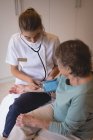 Фізіотерапевт перевіряє артеріальний тиск літньої жінки вдома — стокове фото