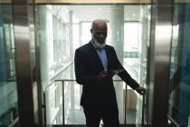 Homme d'affaires utilisant la tablette dans l'ascenseur dans le bureau — Photo de stock