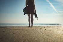 Visão traseira da mulher de pé na praia do mar em um dia ensolarado — Fotografia de Stock