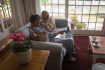 Старша пара використовує ноутбук на дивані вдома — стокове фото