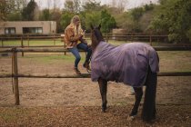 Дівчина з конем, використовуючи мобільний телефон на ранчо — стокове фото