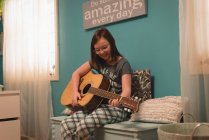 Дівчина грає на гітарі в спальні вдома — стокове фото