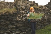 Schöne Wanderin lehnt sich an den Felsen und liest eine Landkarte — Stockfoto