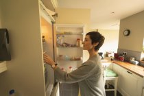 Woman looking into fridge for food at home — Stock Photo