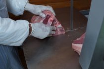 Parte média do açougueiro segurando carne no açougue — Fotografia de Stock