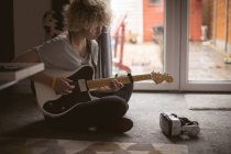 Junge Frau spielt zu Hause im Wohnzimmer Gitarre — Stockfoto