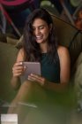 Donna d'affari seduta sul divano e sorridente durante l'utilizzo di tablet in ufficio — Foto stock