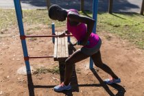 Determined female athlete with dumbbells exercising near the bars — Stock Photo