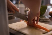 Середина жінки, що ріже моркву на кухні вдома — стокове фото