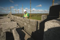 Інженер стоїть біля стіни на будівельному майданчику в сонячний день — стокове фото