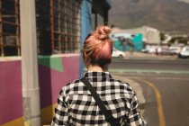 Visão traseira da jovem mulher andando em uma estrada — Fotografia de Stock