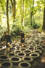Homens aptos a treinar sobre pneus curso de obstáculo no acampamento de inicialização — Fotografia de Stock