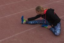 Une athlète féminine s'échauffe sur la piste de course — Photo de stock