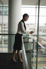 Geschäftsfrau mit Handy am Geländer im Büro — Stockfoto