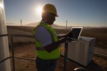 Engineer using a laptop at entrance of a wind mill at a wind farm — Stock Photo