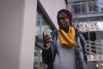 Молодая женщина с мобильного телефона на городской улице — стоковое фото