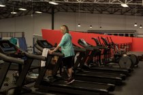 Mujer madura discapacitada haciendo ejercicio en la cinta de correr en el gimnasio - foto de stock