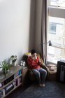 Homme prenant un café tout en utilisant un téléphone portable dans le salon à la maison — Photo de stock