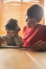 Мати навчає сина на цифровому планшеті вдома — стокове фото