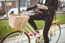 Низька частина жінки на велосипеді за допомогою мобільного телефону — стокове фото