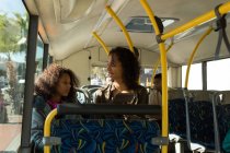 Madre e hija usando tableta digital mientras viajan en el autobús - foto de stock