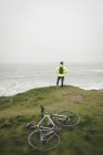 Vista posteriore dell'uomo in piedi sulla collina sulla costa del mare — Foto stock