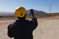 Ingegnere che fotografa un mulino a vento in un parco eolico — Foto stock
