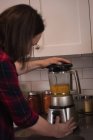 Женщина с помощью смесителя шлифовальный станок на кухне дома — стоковое фото