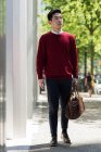 Young man walking on the pavement with a bag — Stock Photo