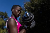 Close-up de atleta feminino exercitando com halteres — Fotografia de Stock
