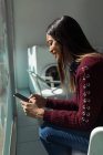 Молода жінка використовує телефон під час очікування прання — стокове фото